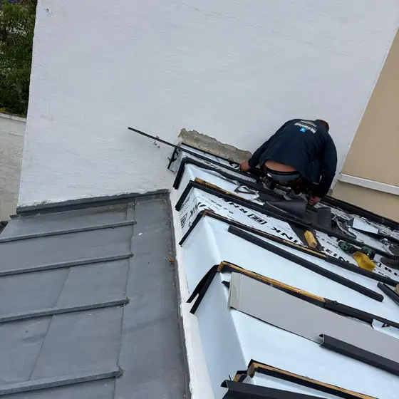 Couvreur CN Toiture posant une membrane d'étanchéité et des rives en zinc pour stopper une infiltration
