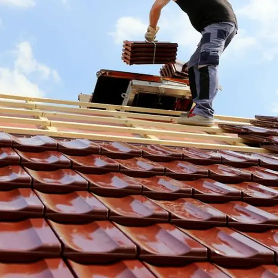 Couvreur CN Toiture portant des tuiles mécaniques sur des liteaux neufs pour une réparation de toiture